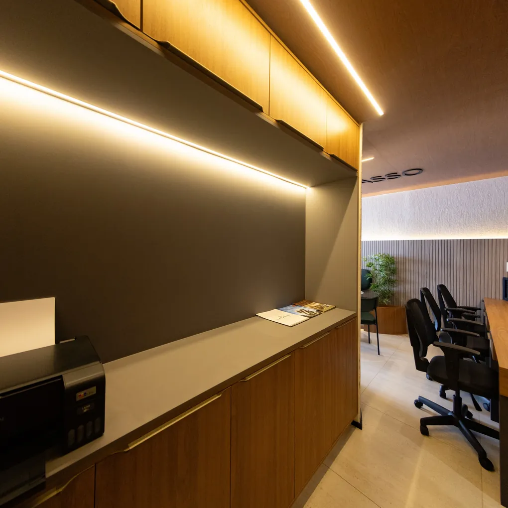 Sala comercial com armários em madeira, bancada e iluminação linear embutida